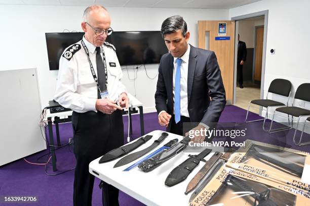 Britain's Prime Minister Rishi Sunak and Metropolitan Police Commissioner Mark Rowley look at knives and machetes seized from knife attacks during a...