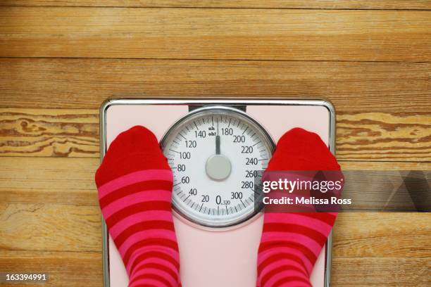 pink striped socks standing on pink scale - pink sock image stock pictures, royalty-free photos & images