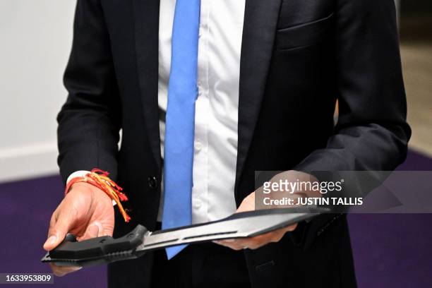 Britain's Prime Minister Rishi Sunak holds a machete seized from knife attacks during a visit to the Kilburn police station, northwest of London, on...