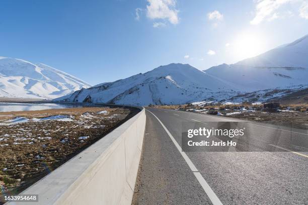 snowy mountains and curved asphalt roads in the wild - point de fuite photos et images de collection