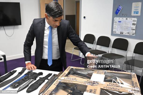 Britain's Prime Minister Rishi Sunak looks at knives and machetes seized from knife attacks during a visit to the Kilburn police station, northwest...