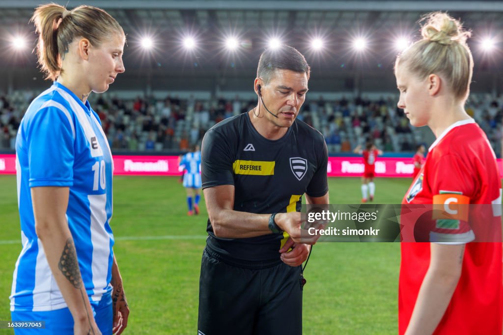 Referee with team captions on football pitch