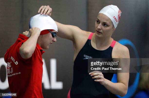 Keri-Anne Payne helps Eleanor Faulker with her swimming cap before they compete in the Women's 1500m on day three of the 2013 British Gas...
