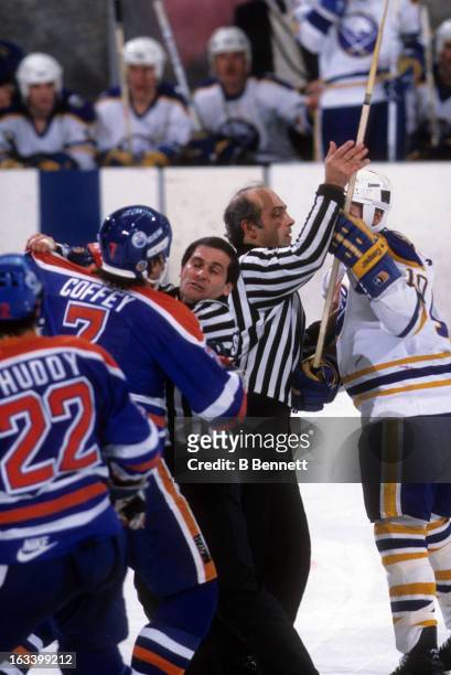 Linesman John D'Amico holds back Craig Ramsay of the Buffalo Sabres as Paul Coffey of the Edmonton Oilers tries to get at him circa 1984 at the...