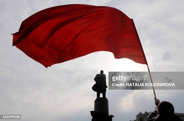 Supporter of the Russian Communist party waves a flag near a monument dedicated to Soviet Union founder Vladimir Lenin in Moscow on May 1 for the May...
