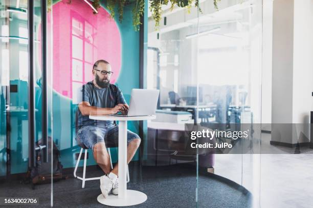 adult man coding on laptop at creative coworking office - creative space stock pictures, royalty-free photos & images