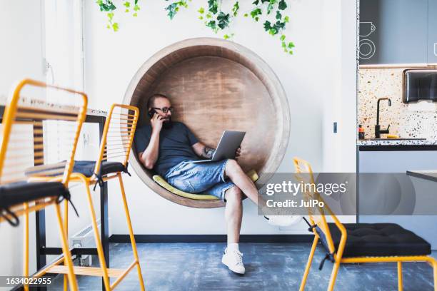 homme mûr travaillant dans un espace de cuisine de bureau parlant par mobile - short photos et images de collection