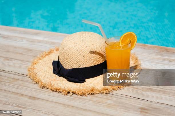 fresh squeezed orange juice and a beautiful straw hat by the pool. - aura stock pictures, royalty-free photos & images