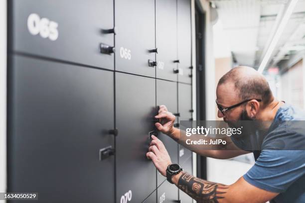 adult man opening his locker at modern coworking - combination lock stock pictures, royalty-free photos & images