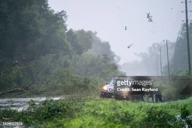 People work to free a vehicle stuck on the shoulder amid storm debris as Hurricane Idalia crosses the state on August 30, 2023 near Mayo, Florida....