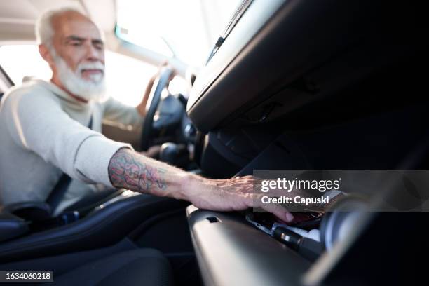 man searchinjg for an object in the glove compartment - glove box stock pictures, royalty-free photos & images