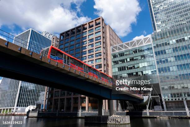 Train on elevated tracks crosses South Dock from Heron Quays station at the heart of Canary Wharf financial district on 15th August 2023 in London,...