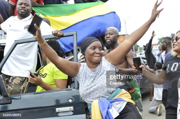 Residents gesture and hold a Gabon national flag as they celebrate in Libreville on August 30, 2023 after a group of Gabonese military officers...
