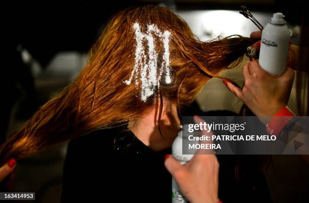 Hair-stylists prepare a model during the Saymyname's Autumn/Winter 2013-2014 collection show at the 40th edition of the Moda Lisboa Lisbon Fashion...
