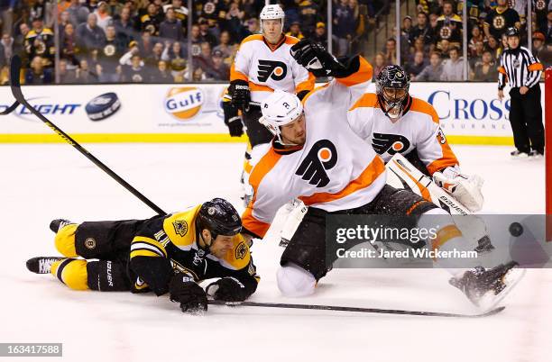 Gregory Campbell of the Boston Bruins and Nicklas Grossmann of the Philadelphia Flyers fall to the ice while battling for the puck during the game on...