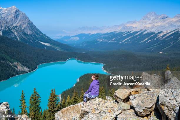 woman relaxes above peyto lake, looks off to view - peytomeer stockfoto's en -beelden