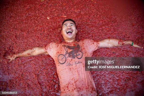 Reveller lies on a street flooded with tomato pulp during the "Tomatina" annual food-battle in the Spanish eastern town of Bunol, on August 30, 2023....