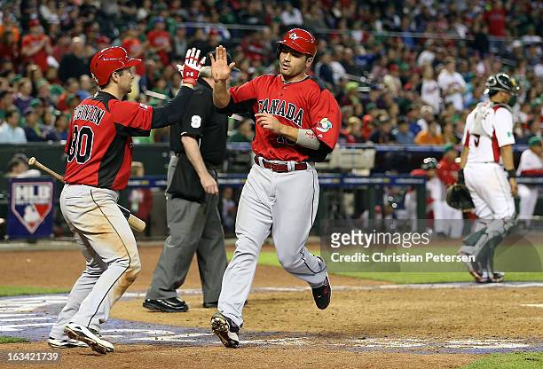 Joey Votto of Canada high-fives Chris Robinson after scoring a eighth inning run against Mexico during the World Baseball Classic First Round Group D...