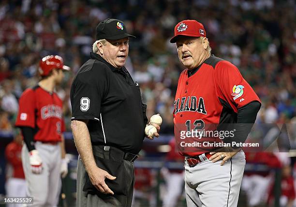 Manager Ernie Whitt of Canada talks with home plate umpire Brian Gorman after objects were thrown onto the field by fans during the World Baseball...