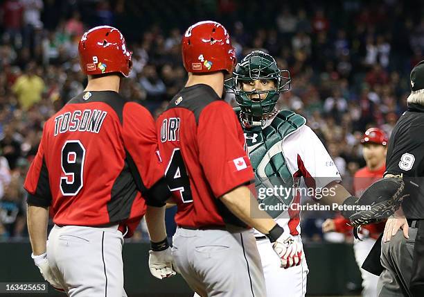 Catcher Sebastian Valle of Mexico reacts to Pete Orr and Rene Tosoni of Canada as both teams run onto the field during the World Baseball Classic...