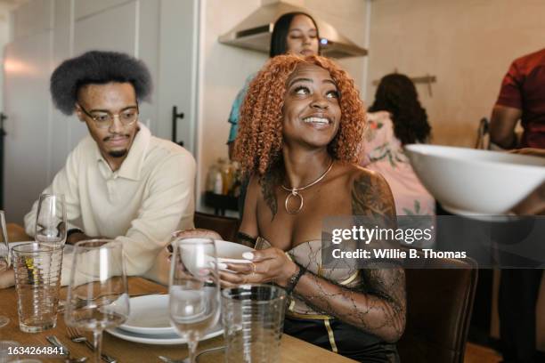 african american woman being served food at dinner party with friends - verre vin rouge photos et images de collection