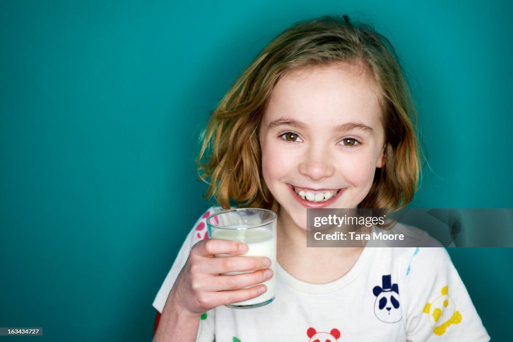 Young girl smiling and holding glass of milk