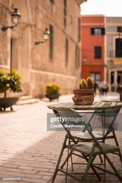 rustic folding chairs next to small table in historic area of ciutadella, menorca, spain - menorca stockfoto's en -beelden