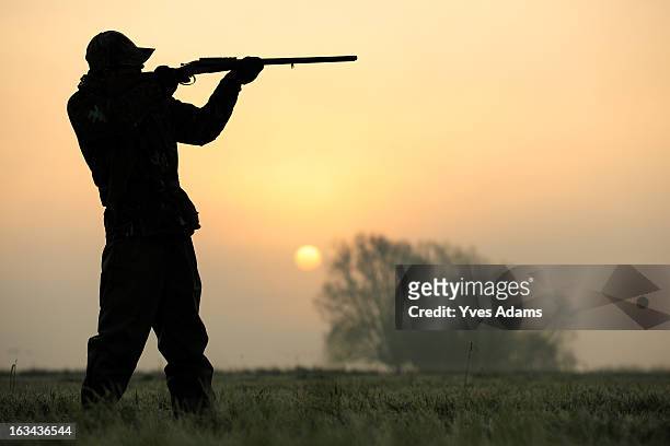 silhouette of a hunter aiming his shotgun - pic hunter imagens e fotografias de stock