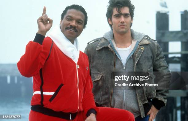 Billy Dee Williams pointing out something to Ken Wahl at dock in a scene from the television series 'Double Dare', 1985.