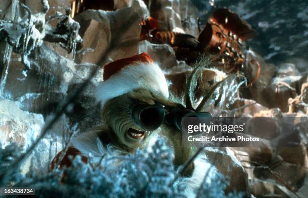 Jim Carrey looking through binoculars in a scene from the film 'How The Grinch Stole Christmas', 2000.
