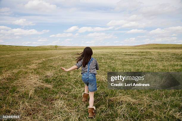 young girl running in green prairie field - alberta prairie stock pictures, royalty-free photos & images