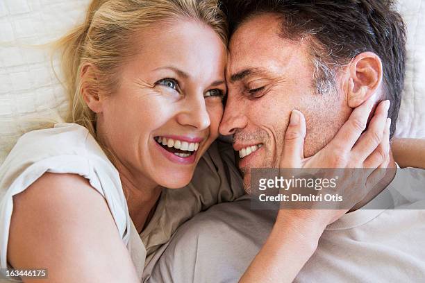 couple in romantic embrace, woman laughing - brunette woman bed stock pictures, royalty-free photos & images