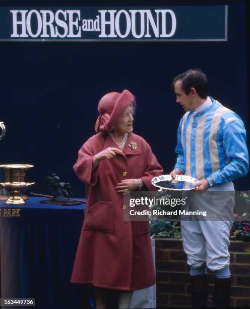 The Queen Mother presents a prize to the winning jockey Major Ollie Ellwood, who rode Norman Conquest to victory in her racing colours, at the...