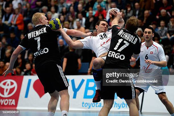 Michal Svajlen of Switzerland is challenged by Patrick Wiencek and Steffen Weinhold of Germany during the DHB International Friendly match between...