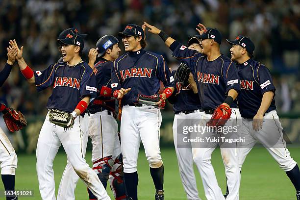 Seiichi Uchikawa and Yoshio Itoi of Team Japan celebrate with teammates defeating Team Chinese Taipei in extra innings in Pool 1, Game 2 in the...