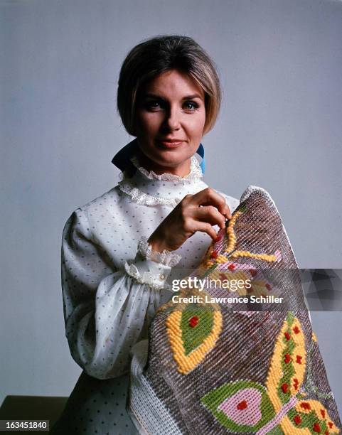 Portrait of American film actress Joanne Woodward, against a white background, as she sews with yarn, Los Angeles, California, 1970.