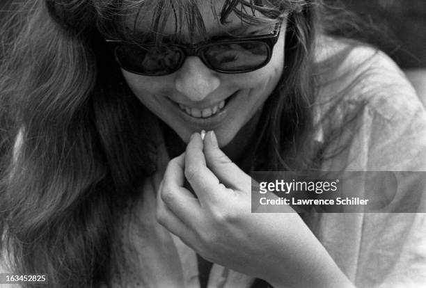 An unidentified young women smiles as she moves to take LSD capsule, California, 1966.
