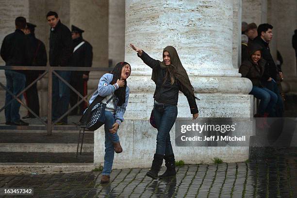 Two women react during a rain shower in St Peter's square on March 10, 2013 in Vatican City, Vatican. Cardinals are set to enter the conclave to...