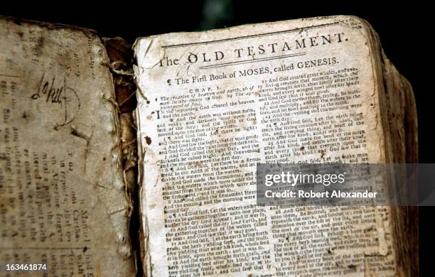 The first page of a well worn 18th Century family bible, opened to 'The First Book of Moses, called Genesis.' The Book of Genesis is the first book...