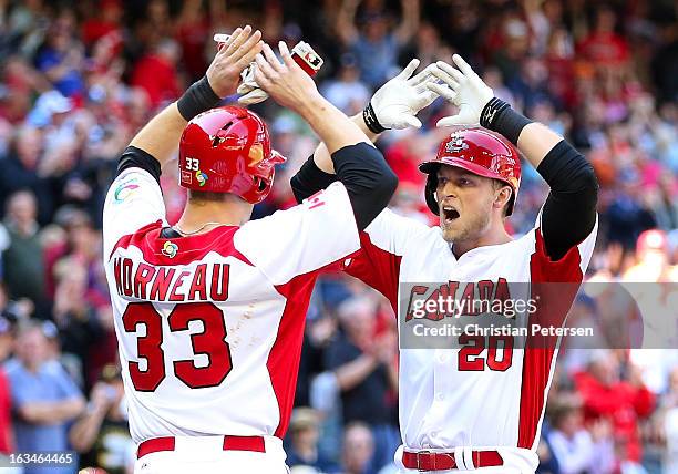 Michael Saunders of Canada high-fives Justin Morneau after hitting a two-run home run against USA during the second inning of the World Baseball...