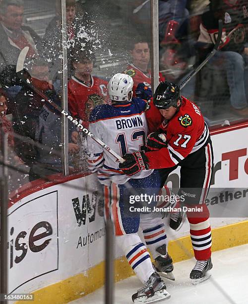 Sheldon Brookbank of the Chicago Blackhawks checks Mike Brown of the Edmonton Oilers at the United Center on March 10, 2013 in Chicago, Illinois.