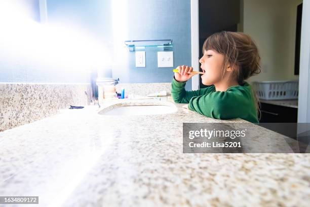 une jeune fille responsable en pyjama se brossant les dents à la maison dans la salle de bain - lavabo photos et images de collection