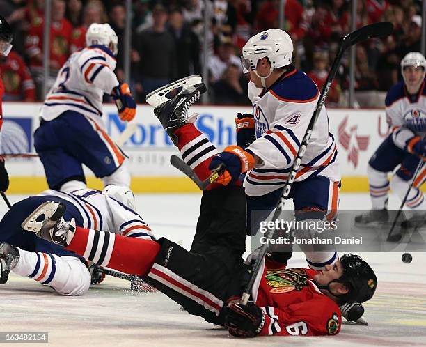 Andrew Shaw of the Chicago Blackhawks is dumped to the ice by Taylor Hall of the Edmonton Oilers at the United Center on March 10, 2013 in Chicago,...