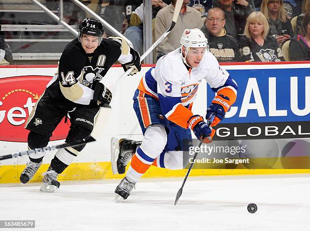 Travis Hamonic of the New York Islanders moves the puck up ice in front of Chris Kunitz of the Pittsburgh Penguins on March 10, 2013 at Consol Energy...