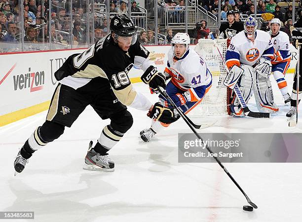 Beau Bennett of the Pittsburgh Penguins reaches for the loose puck in front of Andrew MacDonald of the New York Islanders on March 10, 2013 at Consol...