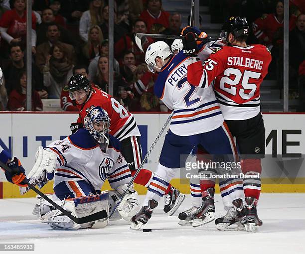 Jeff Petry of the Edmonton Oilers clears the puck in front of Yann Danis while holding off Viktor Stalberg of the Chicago Blackhawks at the United...