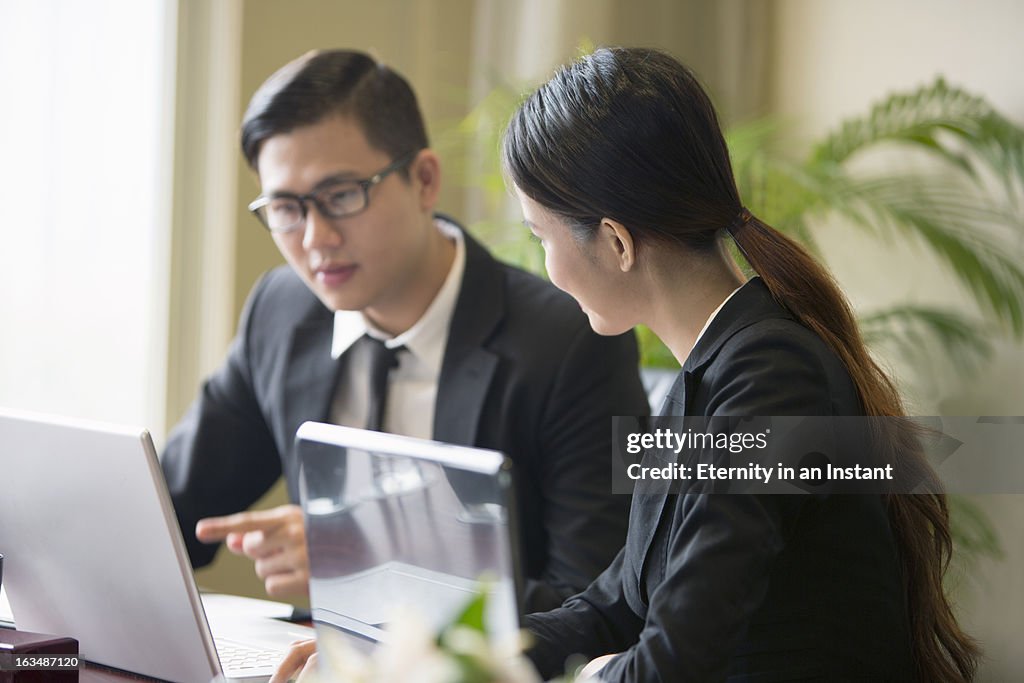 Two people in business meeting with laptops