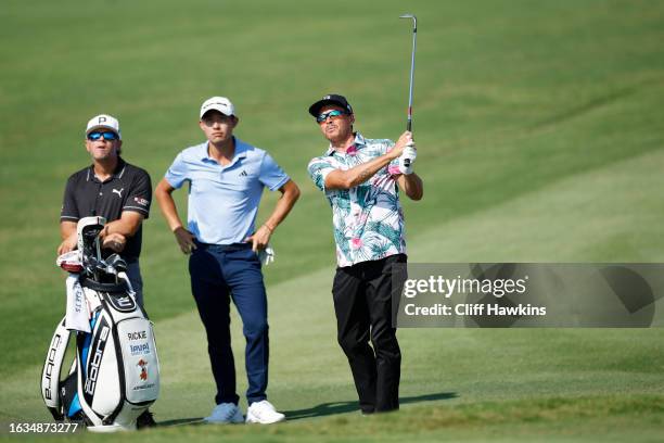 Rickie Fowler of the United States plays a shot as Collin Morikawa of the United States looks on during a practice round prior to the TOUR...