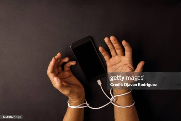 hands of a person tied to a cable connected to a telephone. concept addition to mobile technology. - abuse stock pictures, royalty-free photos & images