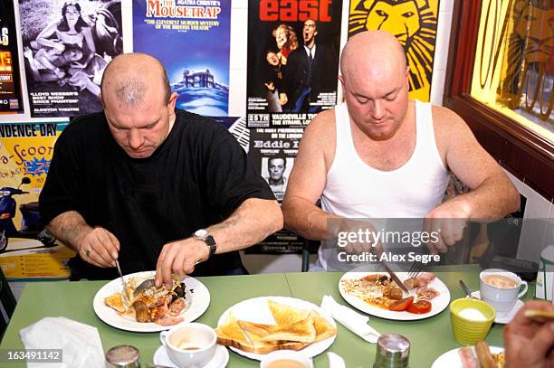 Two workmen eating a fried full English breakfast in cafe